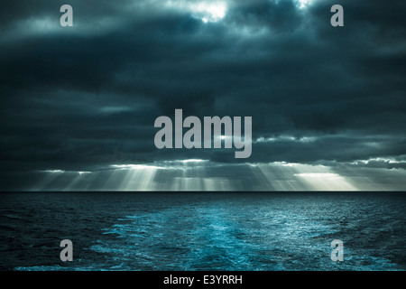 Sun rays shining through early morning cloud over Atlantic Ocean. View from deck of ship Stock Photo