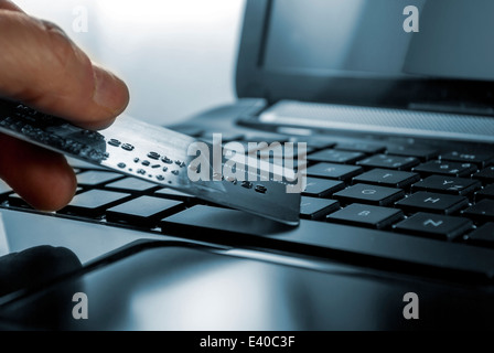 mans hand with credit card and open black laptop keyboard Stock Photo
