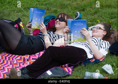 Two young women lying on blanket on grass reading programme at Hay Festival 2014 ©Jeff Morgan Stock Photo