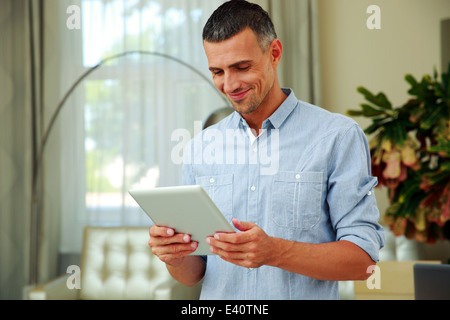Portrait of a smiling man using tablet computer at home Stock Photo