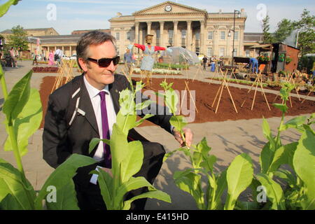 Huddersfield, West Yorkshire, UK. 2nd July, 2014. Commuter, Peter Slee, Deputy Vice Chancellor, Huddersfield University admires farm. French farmers, vegetable plots, sheep, chickens, pigs & a cow appeared overnight in St George’s Square to greet commuters outside the train station. The working farm, that also features 1700 lettuces & 700kg of vegetables, marks the finale of the 100-day Yorkshire Festival 2014, celebrating The Grand Depart coming to the county. Credit:  Deborah Vernon/Alamy Live News Stock Photo