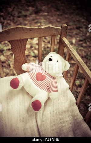 A teddy bear left behind in a vintage baby crib.