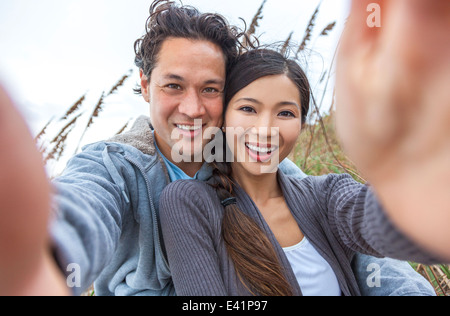 Man & woman Asian couple, boyfriend girlfriend in bikini, taking vacation selfie photograph at the beach Stock Photo