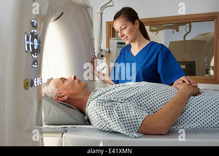 Radiographer reassuring man going into CT scanner Stock Photo