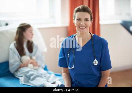 Nurse sitting on end of patient's bed Stock Photo