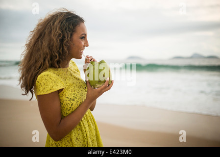 Young woman drinking coconut milk on Ipanema Beach, Rio de Janeiro, Brazil Stock Photo