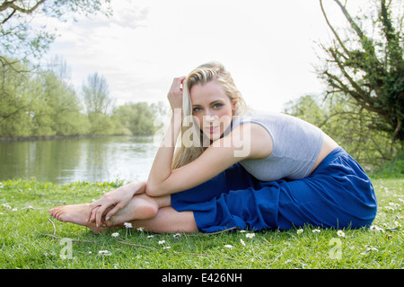 Portrait of flexible young woman exercising near lake