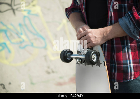 Mid section of young man holding skateboard Stock Photo