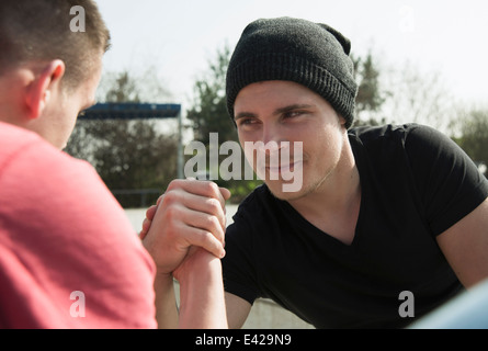 Young men arm-wrestling in skatepark Stock Photo