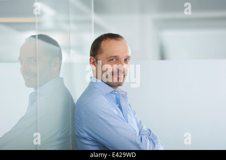Businessman leaning against reflective wall Stock Photo