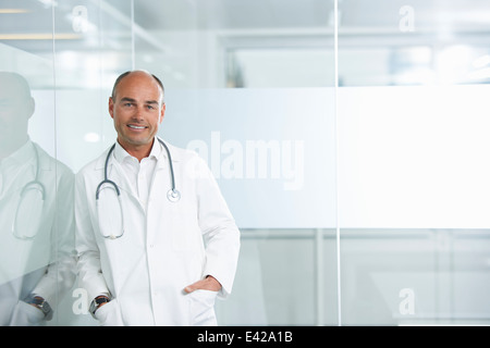 Male doctor leaning against reflective wall Stock Photo
