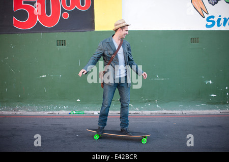 Mid adult male skateboarding on city street Stock Photo