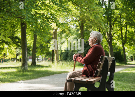 Senior woman sitting on park bench Stock Photo