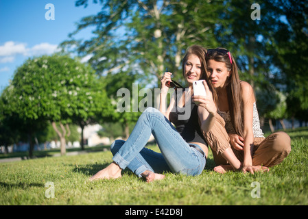 Two young female friends in park taking self portrait on smartphone Stock Photo
