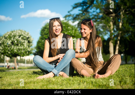 Two young female best friends laughing in park Stock Photo