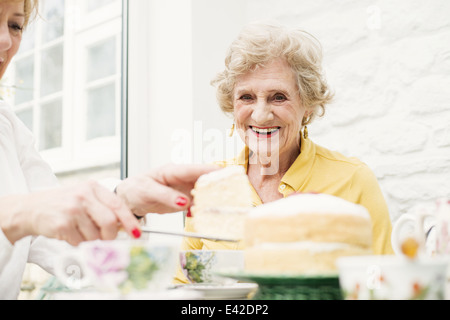 Senior woman and daughter, slicing cake Stock Photo