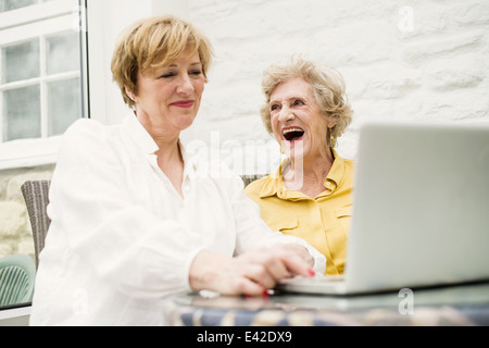 Senior woman and daughter, using laptop