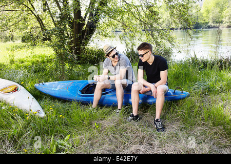 Two young men sitting on a canoe Stock Photo