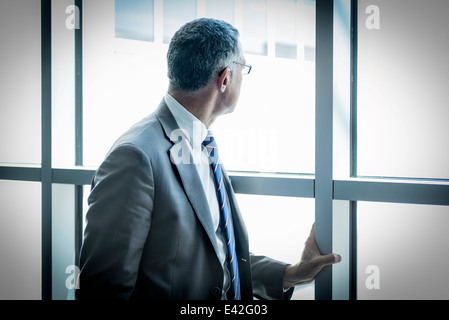 Businessman looking out through glass wall Stock Photo