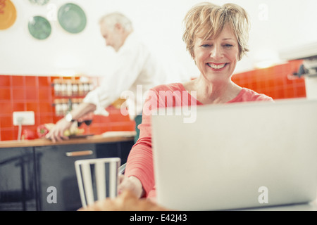Mature woman using laptop in kitchen Stock Photo