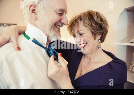 Mature woman putting bow tie on senior man Stock Photo