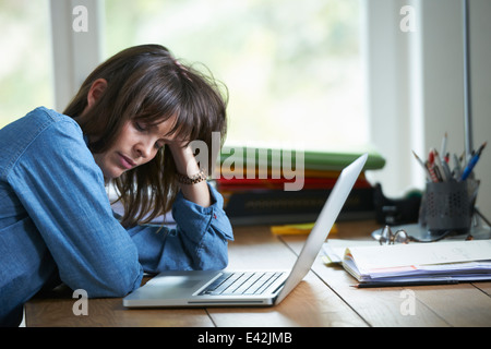 Woman sitting at desk with laptop, eyes closed Stock Photo