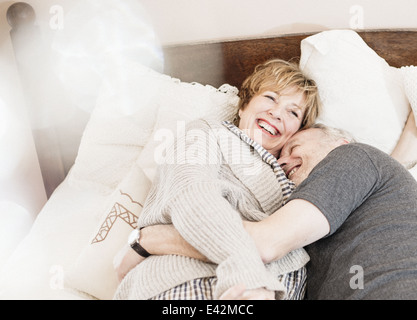 Couple lying on bed laughing Stock Photo