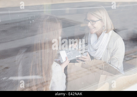 Senior woman and granddaughter looking at shopping in cafe