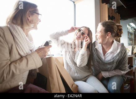 Three generation females trying on sunglasses in shop Stock Photo