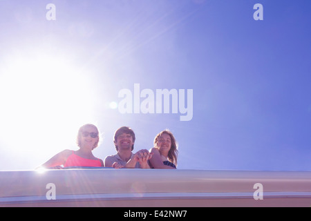 Portrait of three adult friends looking down from yacht Stock Photo