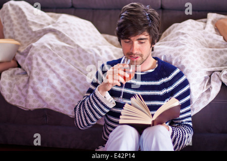 Man reading as two women sleep in yacht cabin Stock Photo