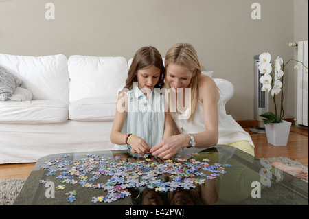 Mother and daughter doing jigsaw puzzle on coffee table Stock Photo
