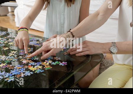 Hands of mother and daughter doing jigsaw puzzle Stock Photo