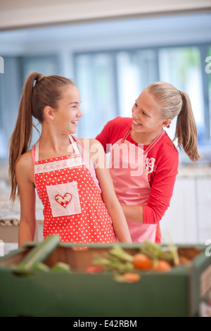 Two teenage girls preparing vegetables in kitchen Stock Photo