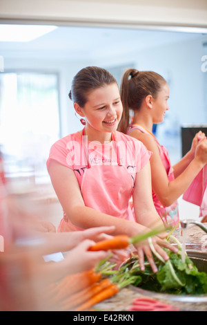 Teenage girls preparing carrots in kitchen Stock Photo