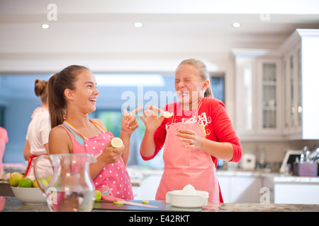 Two teenage girls tasting sour lemons in kitchen Stock Photo