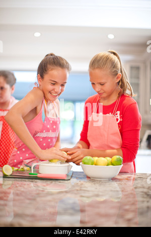 Two teenage girls squeezing lemons in kitchen Stock Photo