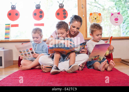 Teacher and pupils reading story books at nursery school Stock Photo