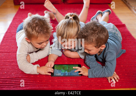 Boys and a girl using digital tablet at nursery school Stock Photo
