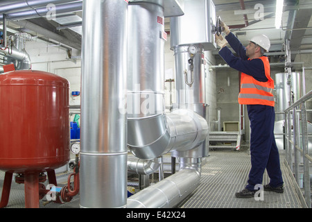 Technician reaching to check pipes in power station Stock Photo