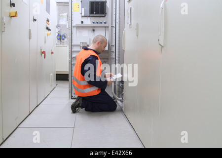 Technician reading paperwork in power station control room Stock Photo