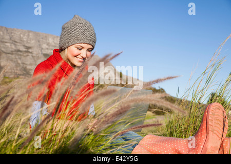 Young woman using laptop in grassy field Stock Photo