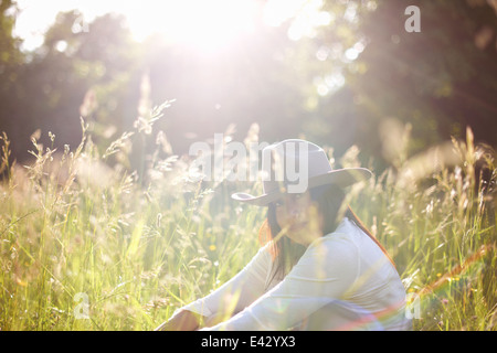 Portrait of mature woman in long grass wearing cowboy hat Stock Photo