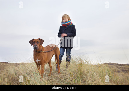 Boy walking his dog in sand dunes at coast Stock Photo