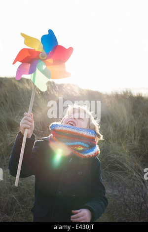 Boy holding up paper windmill at coast Stock Photo