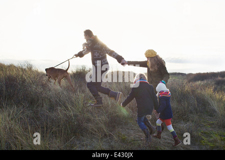 Mid adult couple strolling in sand dunes with their son, daughter and dog Stock Photo