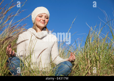 Young woman in yoga lotus position in long grass Stock Photo