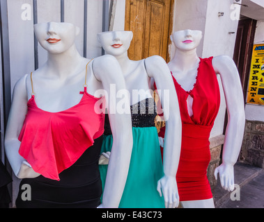 Three white colored mannequins, whose heads are only half a head missing the top from the eyes up, displaying woman's clothes. Stock Photo