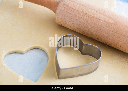 Dough rolled out with heart shape cut out, and heart shaped cookie cutter Stock Photo
