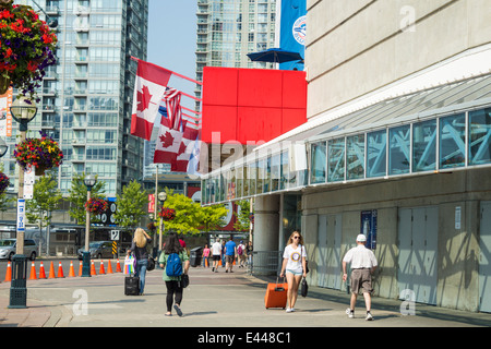 People walking in front of the Rogers Centre in downtown Toronto with the Canadian Flags flying on a summer day Stock Photo